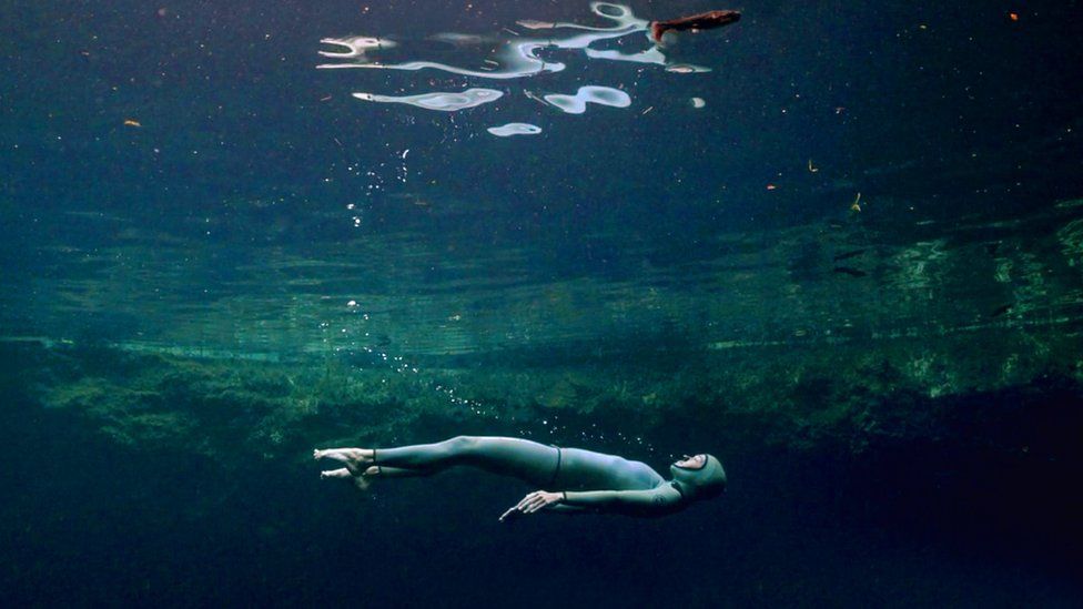 The Deepest Breath, a freediver swims just beneath the surface.