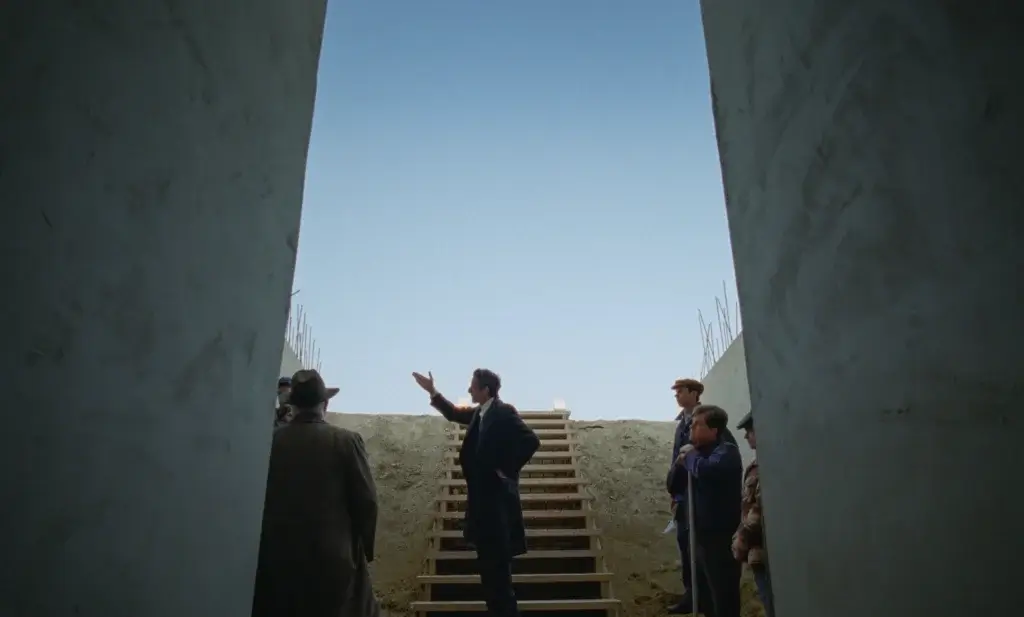 Men stand between concrete blocks with the sky behind