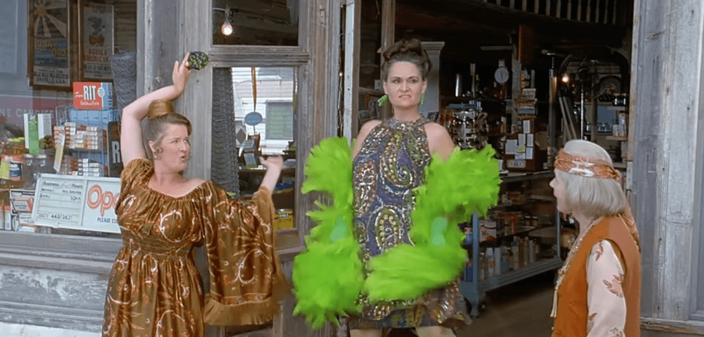 Three ladies pose in flashy outfits.
